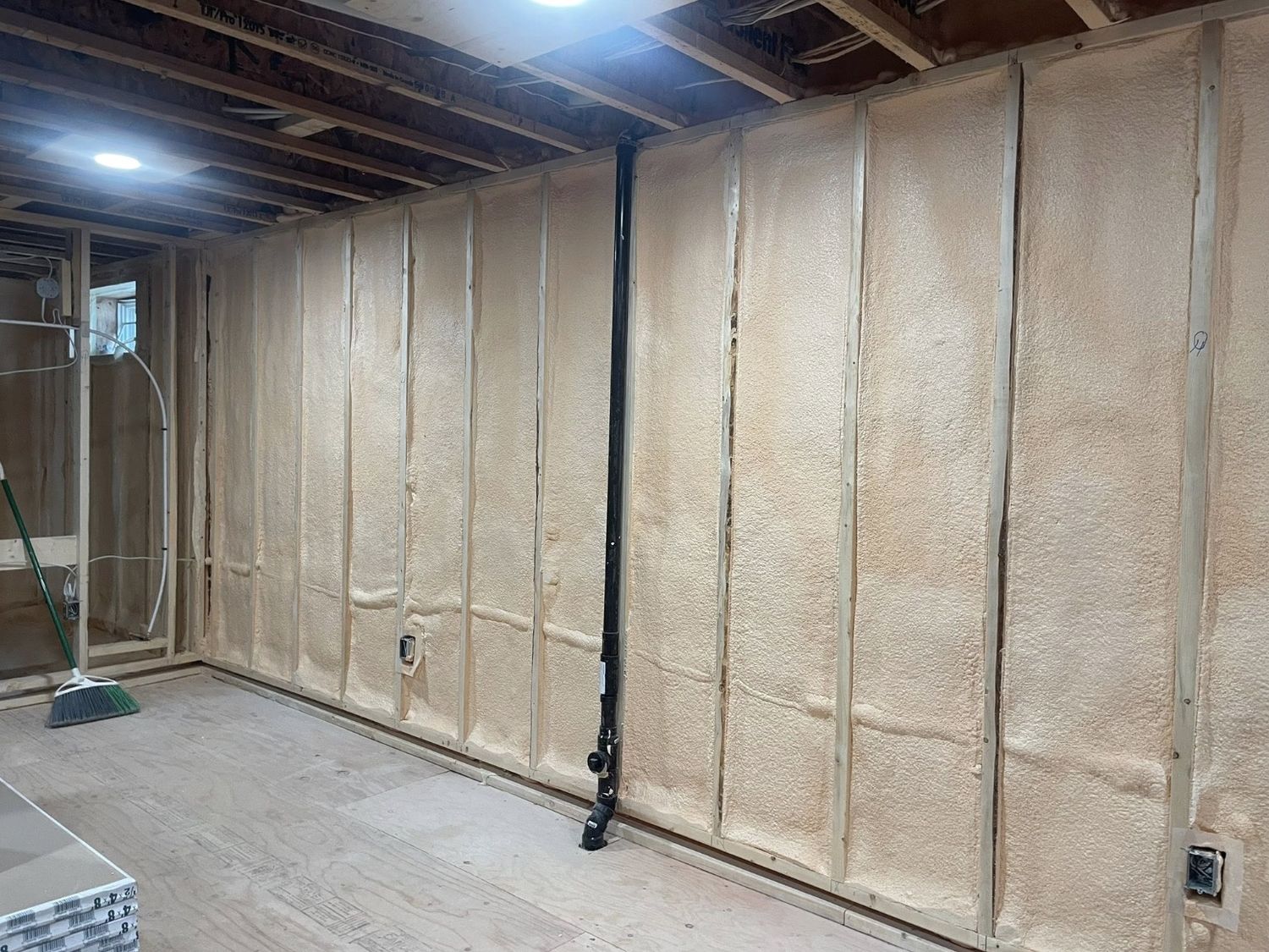 Basement wall fully insulated with spray foam between wood strapping, ready for finishing