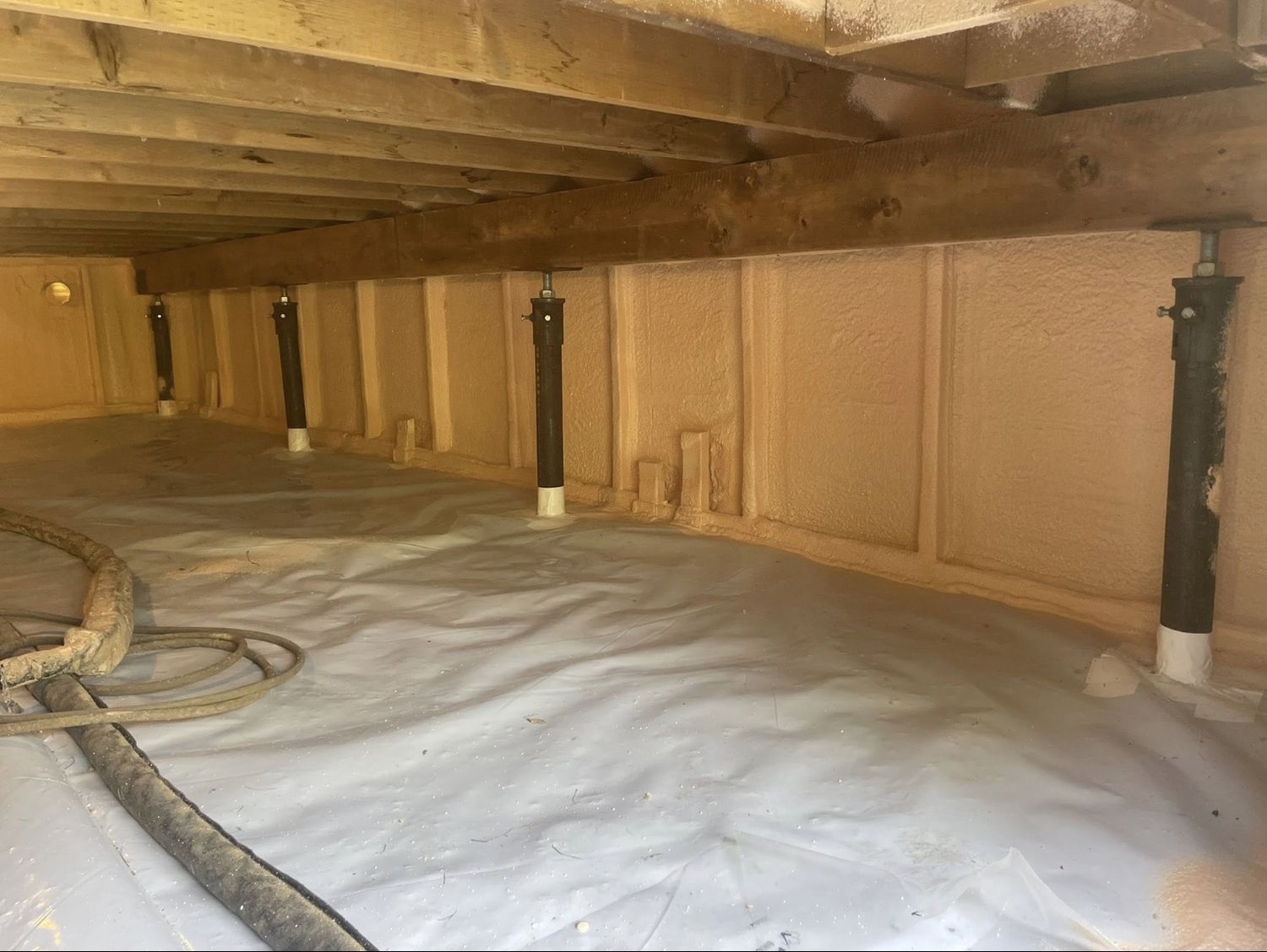 Crawl space with spray foamed perimeter walls, white poly ground cover and steel teleposts
