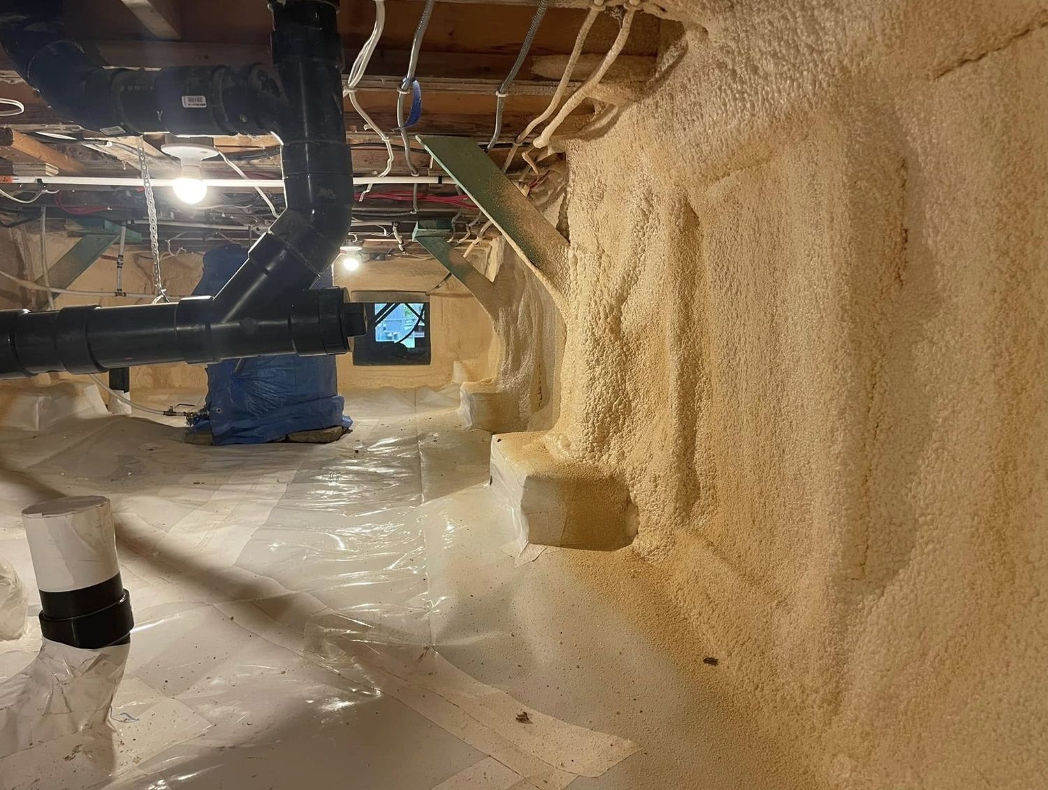 Crawl space with thick spray foam on the walls tied into a sealed poly ground sheet, drain pipes overhead